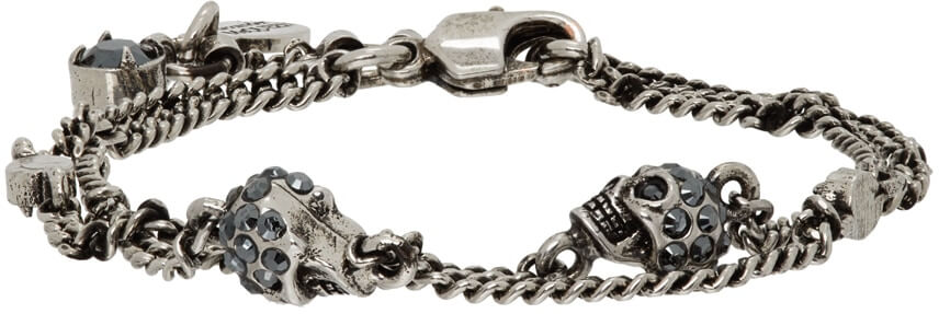 Curb chain bracelet in gunmetal-tone brass. Swarovski crystal-embellished signature skulls throughout. Logo disc at lobster-clasp fastening.